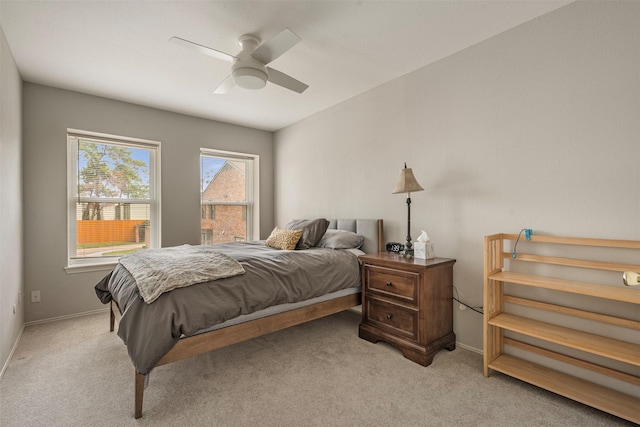 bedroom with a ceiling fan, light carpet, and baseboards