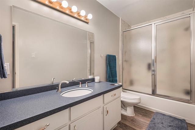 bathroom with bath / shower combo with glass door, vanity, toilet, and wood finished floors