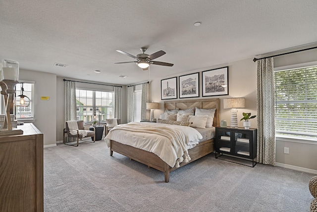 bedroom with baseboards, visible vents, a textured ceiling, and light colored carpet