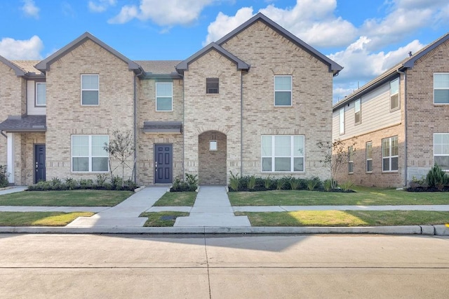 multi unit property featuring brick siding and a front yard