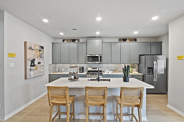 kitchen featuring appliances with stainless steel finishes, a breakfast bar, visible vents, and light wood-style floors