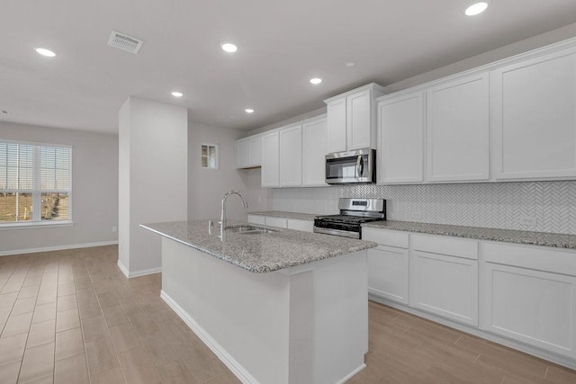 kitchen featuring visible vents, backsplash, appliances with stainless steel finishes, white cabinets, and a sink