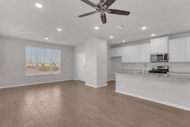 kitchen with visible vents, white cabinets, light wood-style flooring, appliances with stainless steel finishes, and backsplash