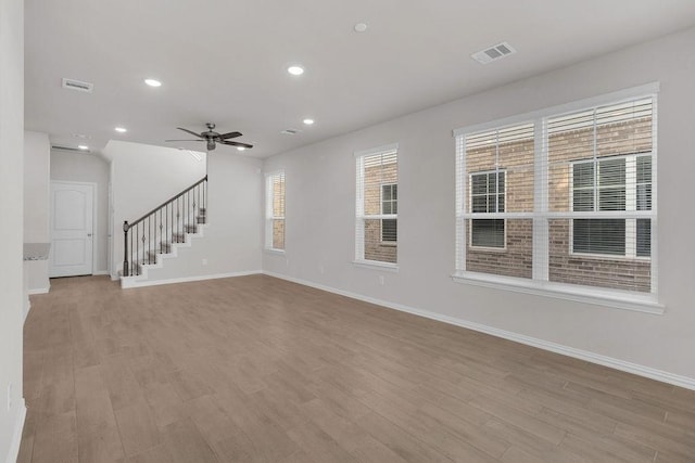 empty room featuring visible vents, stairway, baseboards, and wood finished floors