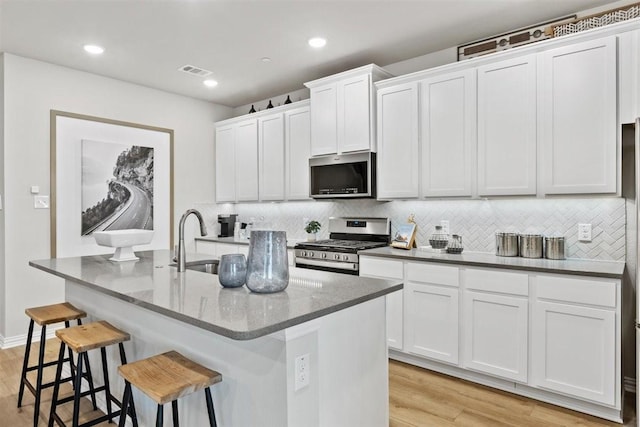 kitchen featuring appliances with stainless steel finishes, a sink, visible vents, and light wood-style floors