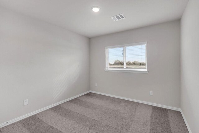 spare room with carpet floors, visible vents, and baseboards