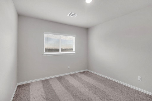 empty room featuring carpet floors, visible vents, and baseboards