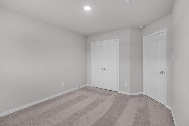 unfurnished bedroom with carpet floors, a closet, and baseboards