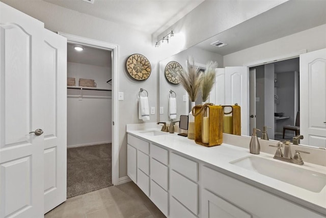 full bathroom featuring double vanity, a sink, visible vents, and a walk in closet