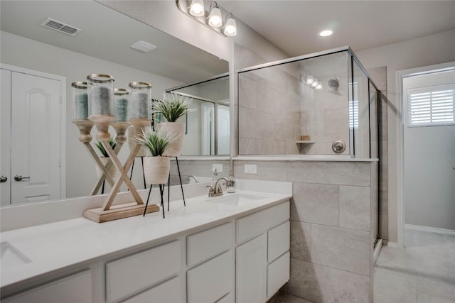 full bathroom featuring double vanity, a sink, visible vents, and a shower stall