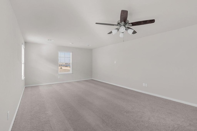 carpeted spare room featuring visible vents, a ceiling fan, and baseboards