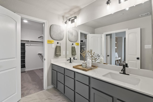 bathroom with marble finish floor, visible vents, a sink, and double vanity