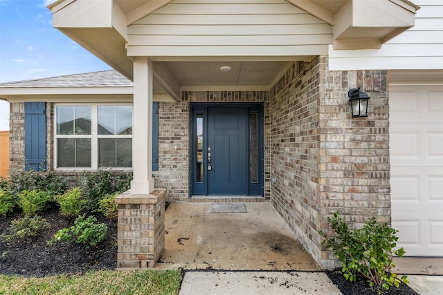 property entrance featuring brick siding, an attached garage, and roof with shingles