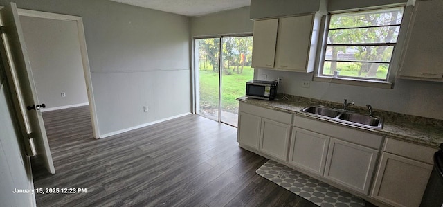 kitchen with dark wood-style floors, a sink, and baseboards