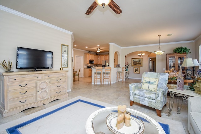 living area featuring ornamental molding, arched walkways, baseboards, and ceiling fan with notable chandelier