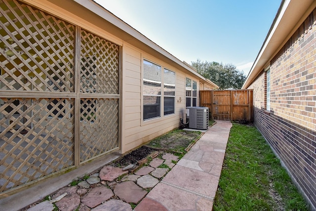 view of property exterior featuring fence, central AC, and brick siding