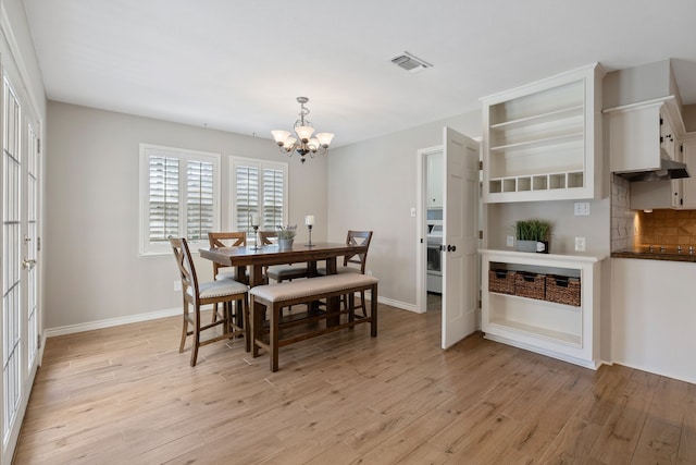 dining room with visible vents, washer / clothes dryer, light wood finished floors, baseboards, and a chandelier