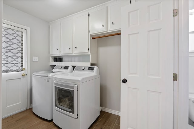 laundry room featuring baseboards, cabinet space, wood finished floors, and washer and clothes dryer