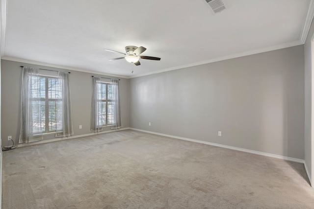 carpeted spare room with a ceiling fan, crown molding, baseboards, and visible vents