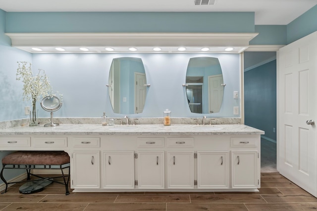 full bath with a sink, visible vents, double vanity, and wood tiled floor