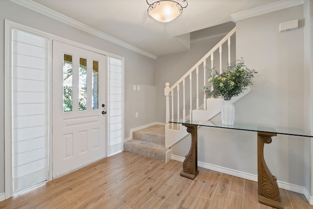 foyer featuring light wood finished floors, stairs, baseboards, and ornamental molding