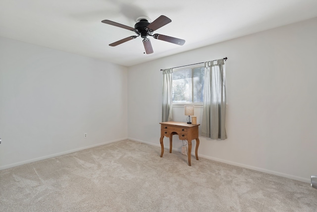 empty room featuring a ceiling fan, light colored carpet, and baseboards