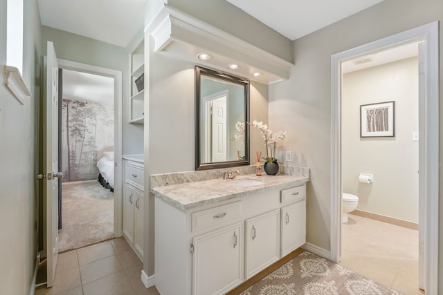 ensuite bathroom featuring vanity, baseboards, ensuite bath, tile patterned floors, and toilet