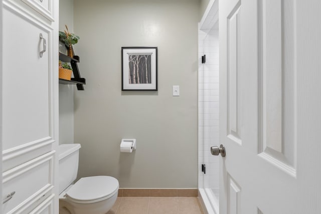 bathroom with baseboards, tiled shower, toilet, and tile patterned flooring