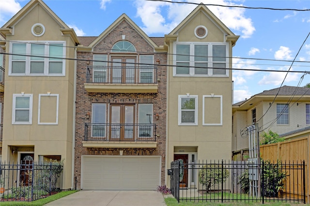 townhome / multi-family property with concrete driveway, stucco siding, an attached garage, fence, and brick siding