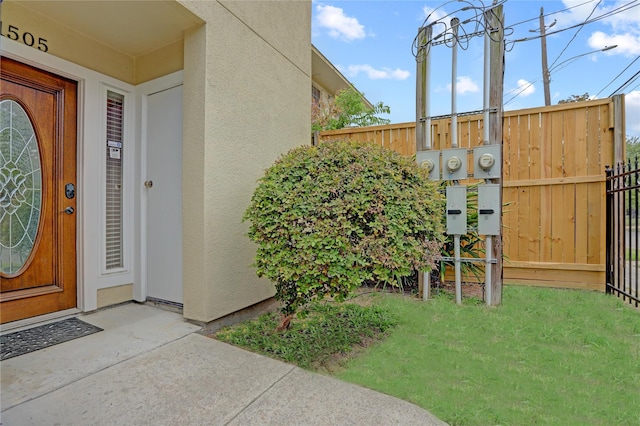 entrance to property with fence and stucco siding