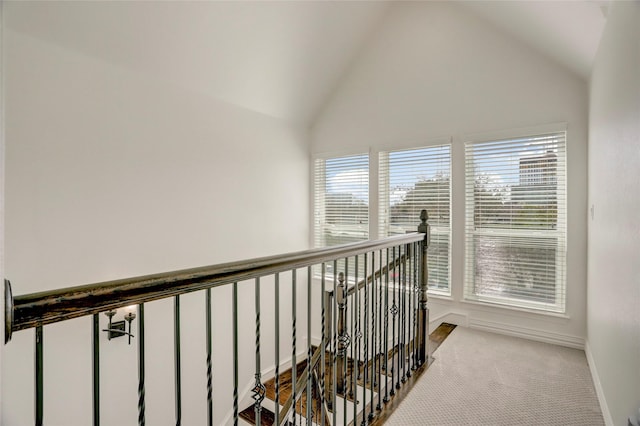 hall featuring high vaulted ceiling, carpet, an upstairs landing, and baseboards