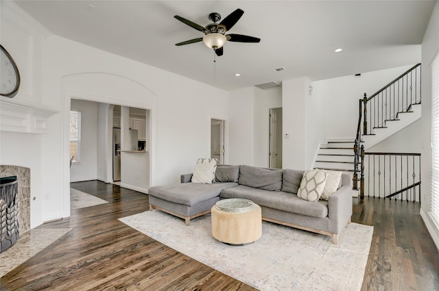 living room featuring recessed lighting, a ceiling fan, stairs, dark wood-style floors, and a tiled fireplace