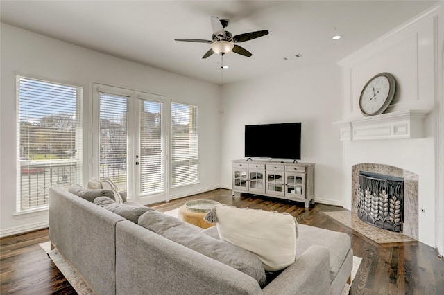 living area with recessed lighting, a fireplace with flush hearth, wood finished floors, baseboards, and a ceiling fan