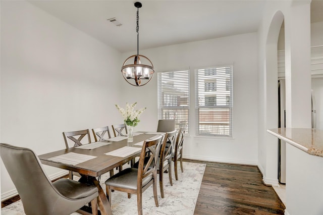 dining area featuring visible vents, baseboards, arched walkways, wood finished floors, and a notable chandelier