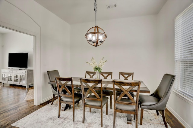 dining area with an inviting chandelier, visible vents, baseboards, and wood finished floors