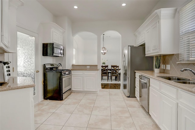 kitchen featuring stainless steel appliances, tasteful backsplash, a sink, and white cabinets