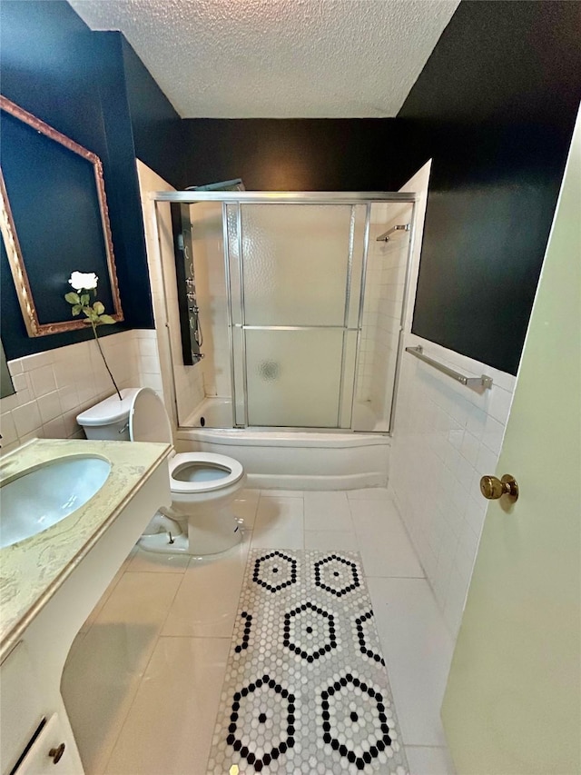 full bathroom with toilet, tile patterned flooring, tile walls, and a textured ceiling