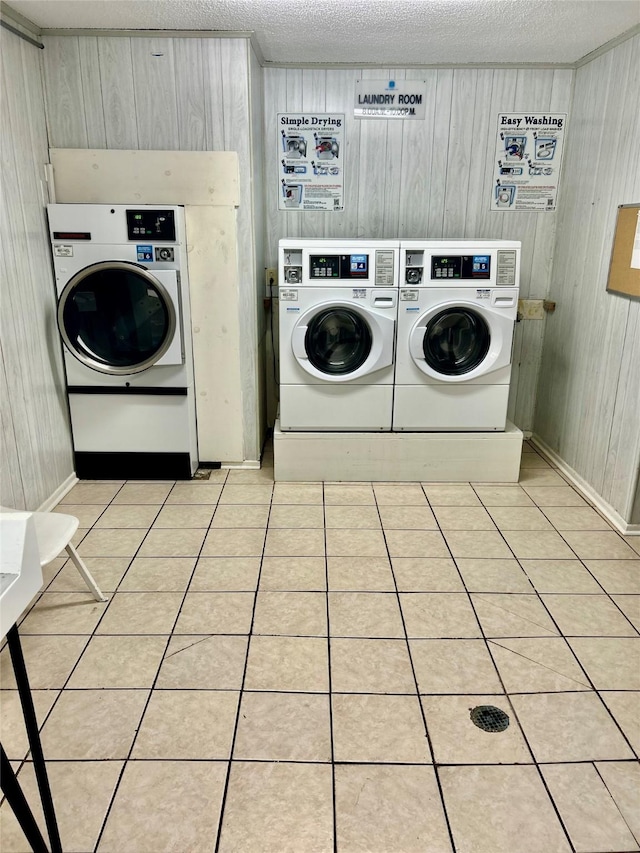 common laundry area with a textured ceiling, separate washer and dryer, and light tile patterned flooring