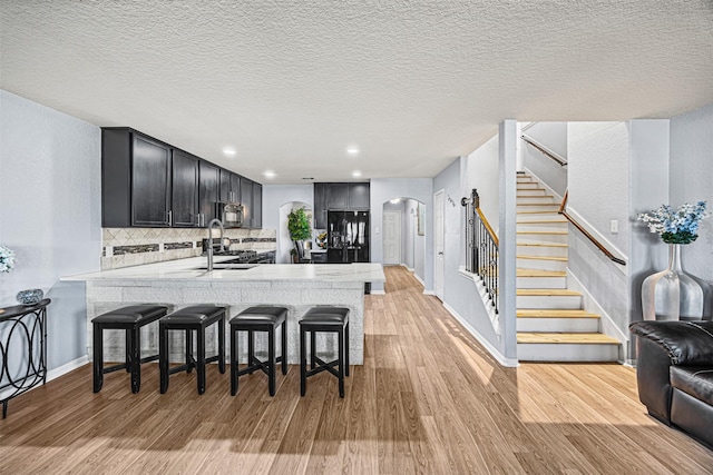 15307 Meandering Post Trl, Houston, TX 77044 - kitchen featuring arched walkways, light countertops, light wood-style flooring, a peninsula, and a kitchen bar