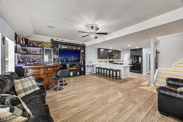 15307 Meandering Post Trl, Houston, TX 77044 - living room featuring a bar, ceiling fan, light wood-style floors, a textured ceiling, and stairs