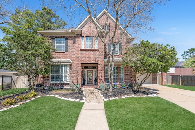 traditional-style house with driveway, brick siding, a front yard, and fence