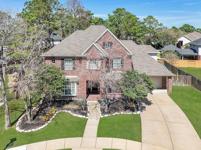 view of front facade with a garage, roof with shingles, fence, a front lawn, and brick siding