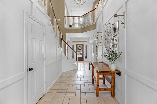 entryway featuring stone tile flooring, a high ceiling, and stairs