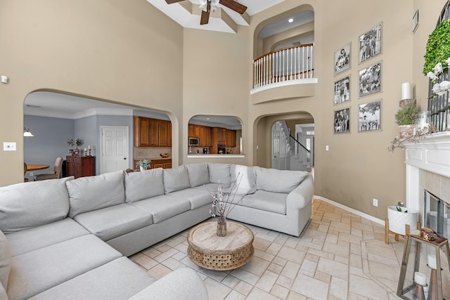 living room featuring arched walkways, stone tile flooring, baseboards, and a tiled fireplace