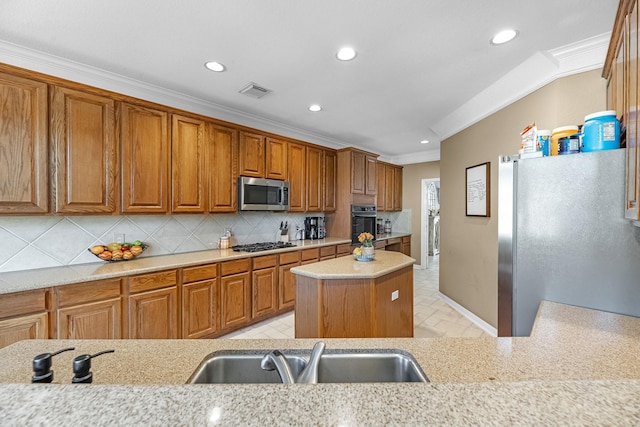 kitchen featuring appliances with stainless steel finishes, brown cabinets, backsplash, ornamental molding, and a sink