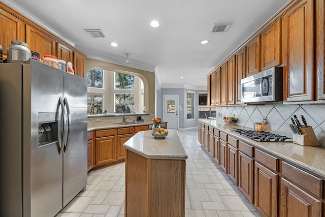 kitchen with tasteful backsplash, stone tile floors, a kitchen island, stainless steel appliances, and crown molding