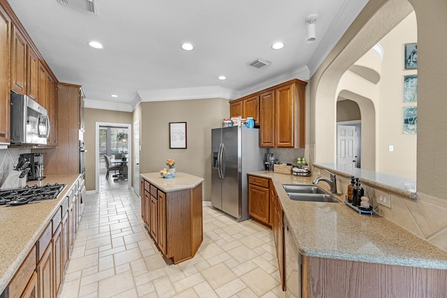 kitchen featuring a sink, visible vents, appliances with stainless steel finishes, a center island, and brown cabinetry