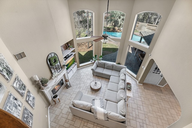 living room featuring a towering ceiling, visible vents, and a ceiling fan