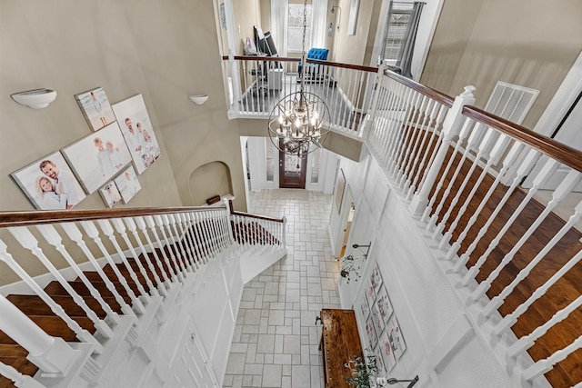 stairway with stone finish flooring, a high ceiling, and visible vents