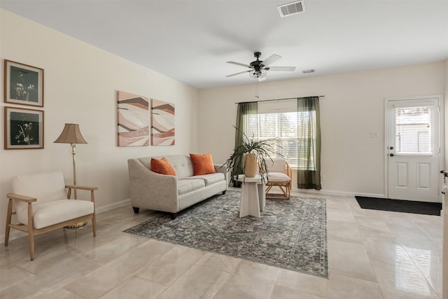 living room featuring a ceiling fan, visible vents, plenty of natural light, and baseboards